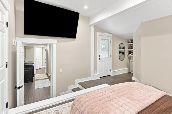 Wood-finish flooring throughout, bright white trim, and a built-in wall-mounted television