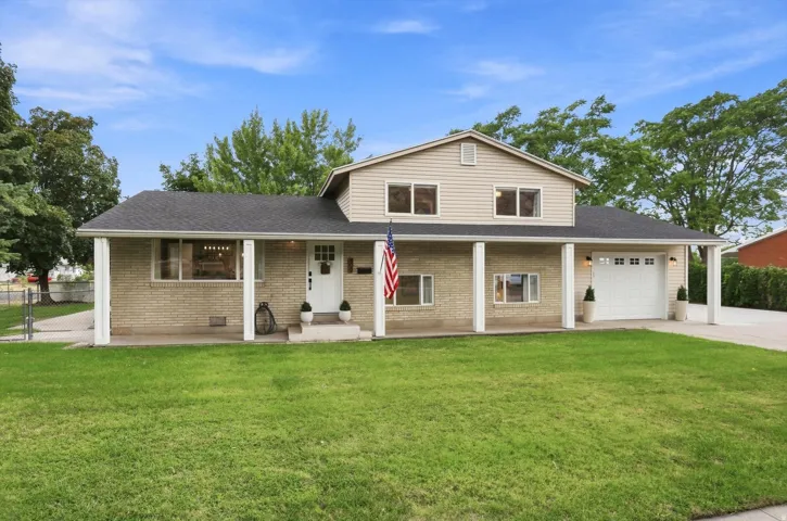 Brick exterior with siding accents, covered front porch, attached garage, and a lush green lawn