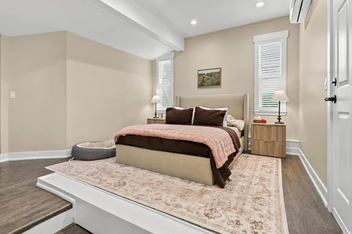 Recessed lighting, wood-finish flooring, white paneled door, step-up platform, and interior window with plantation shutters