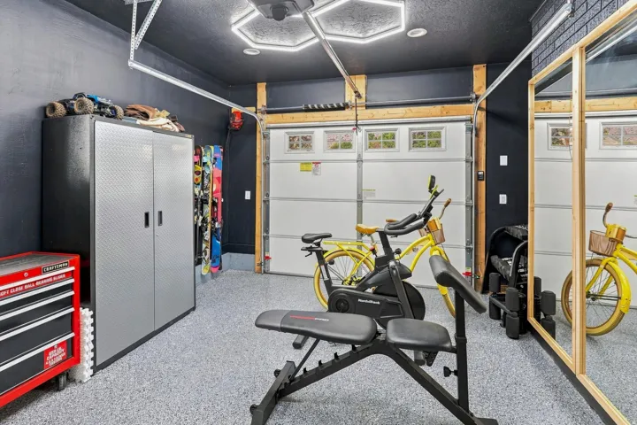 Garage with durable epoxy flooring, overhead hexagonal lighting, built-in storage cabinetry, and paneled garage doors with frosted windows