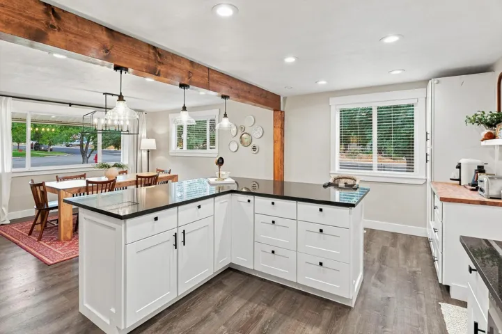 Kitchen featuring a large island with dark countertops, recessed lighting, wood-finish flooring, and white cabinetry with dark hardware