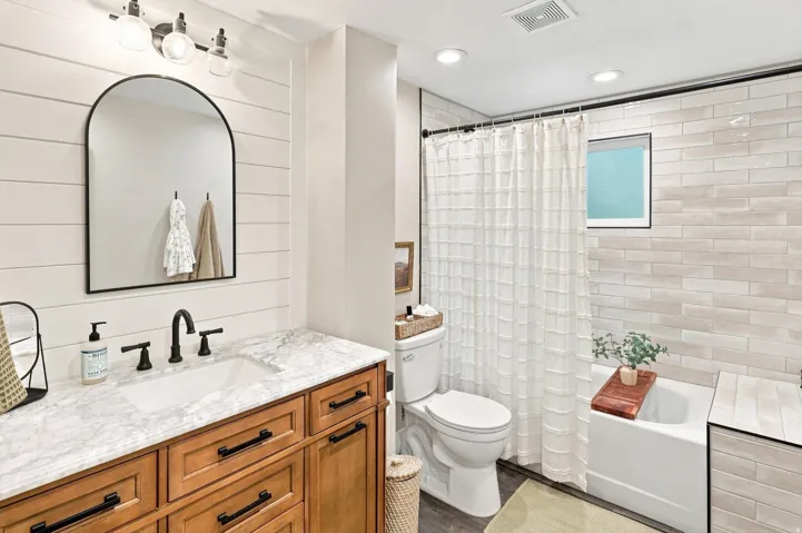 Vanity with wood-finish cabinetry, white countertop, and black hardware