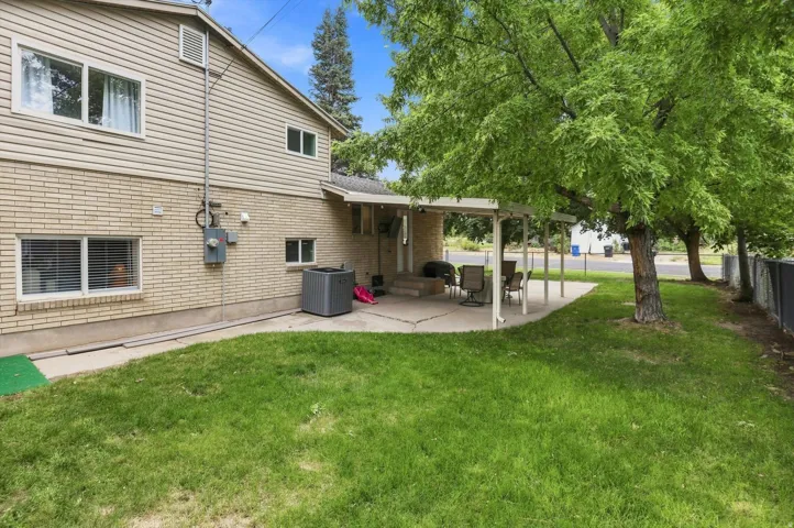 Expansive backyard with a covered patio, mature trees, and a combination brick and siding exterior