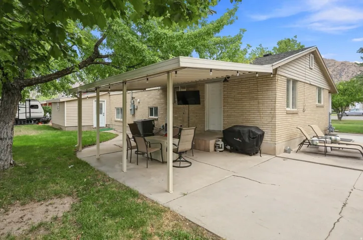 Expansive concrete patio with a covered pergola, string lighting, and direct access to the house