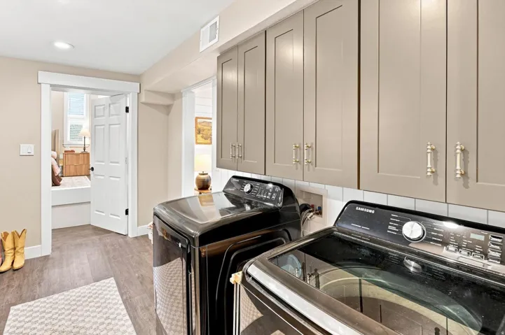 Upper cabinetry with gold-tone hardware, white subway tile backsplash, and wood-finish flooring