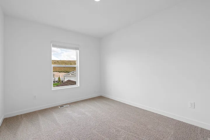 Recessed ceiling lighting, a single window with blinds, and neutral-toned carpeting