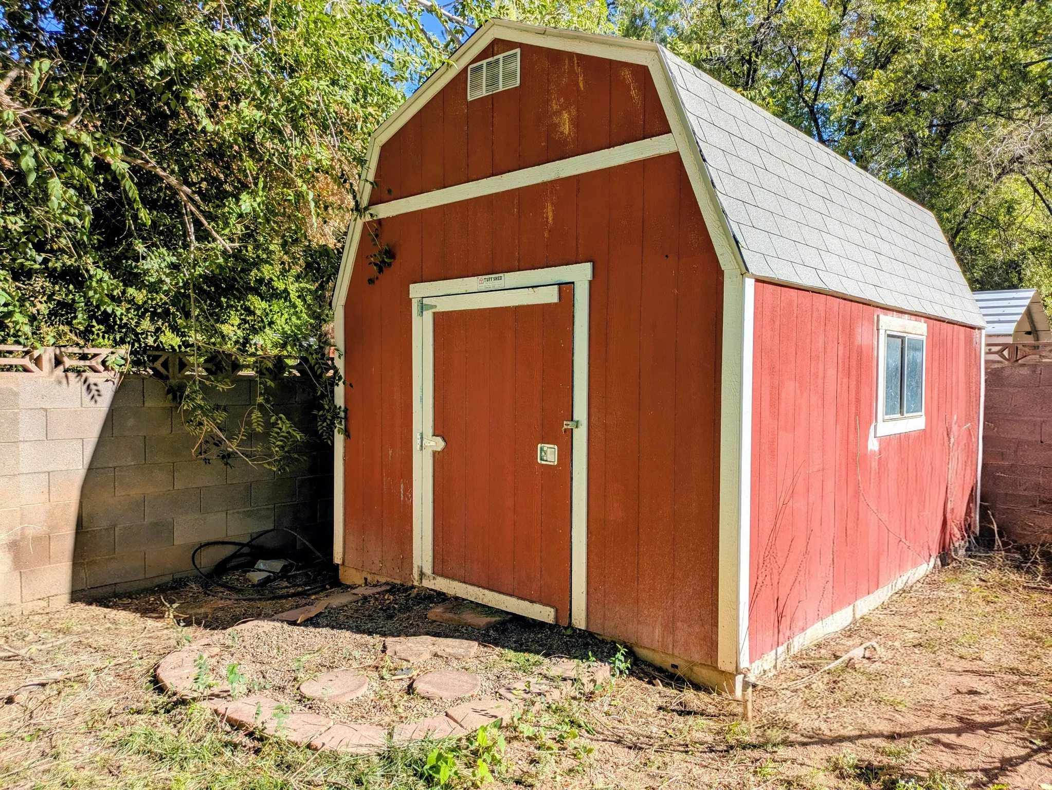 Red exterior shed with a gambrel roof and a single window