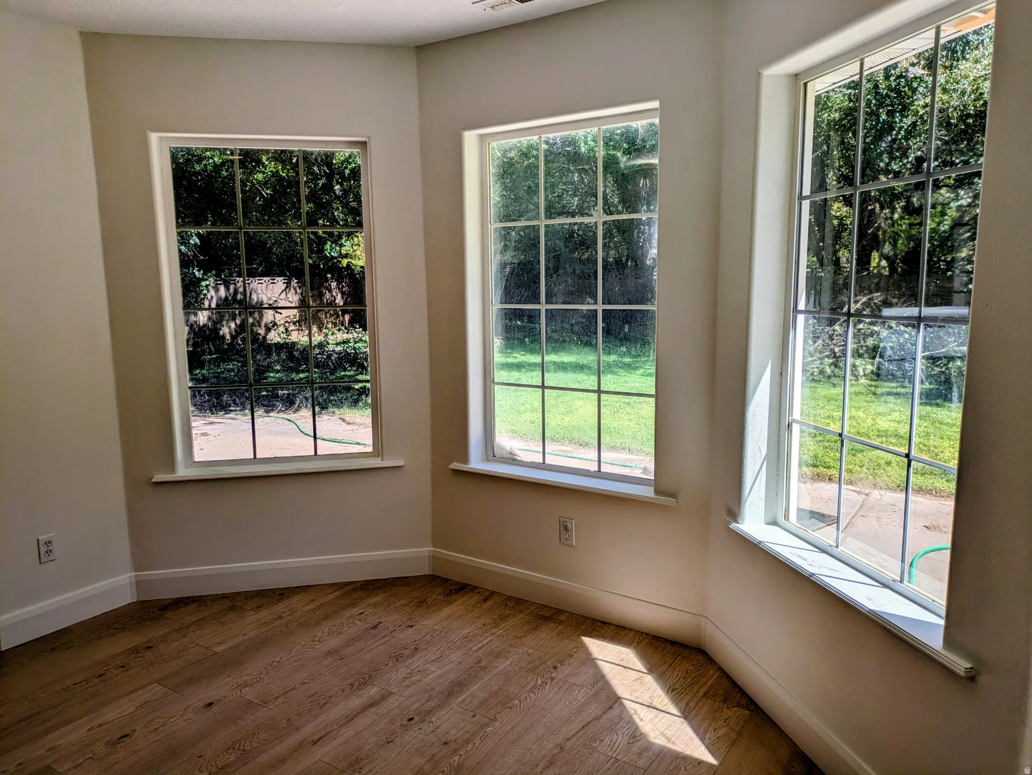 Bright interior space featuring multiple grid-pattern windows, wood-finish flooring, and crisp white trim