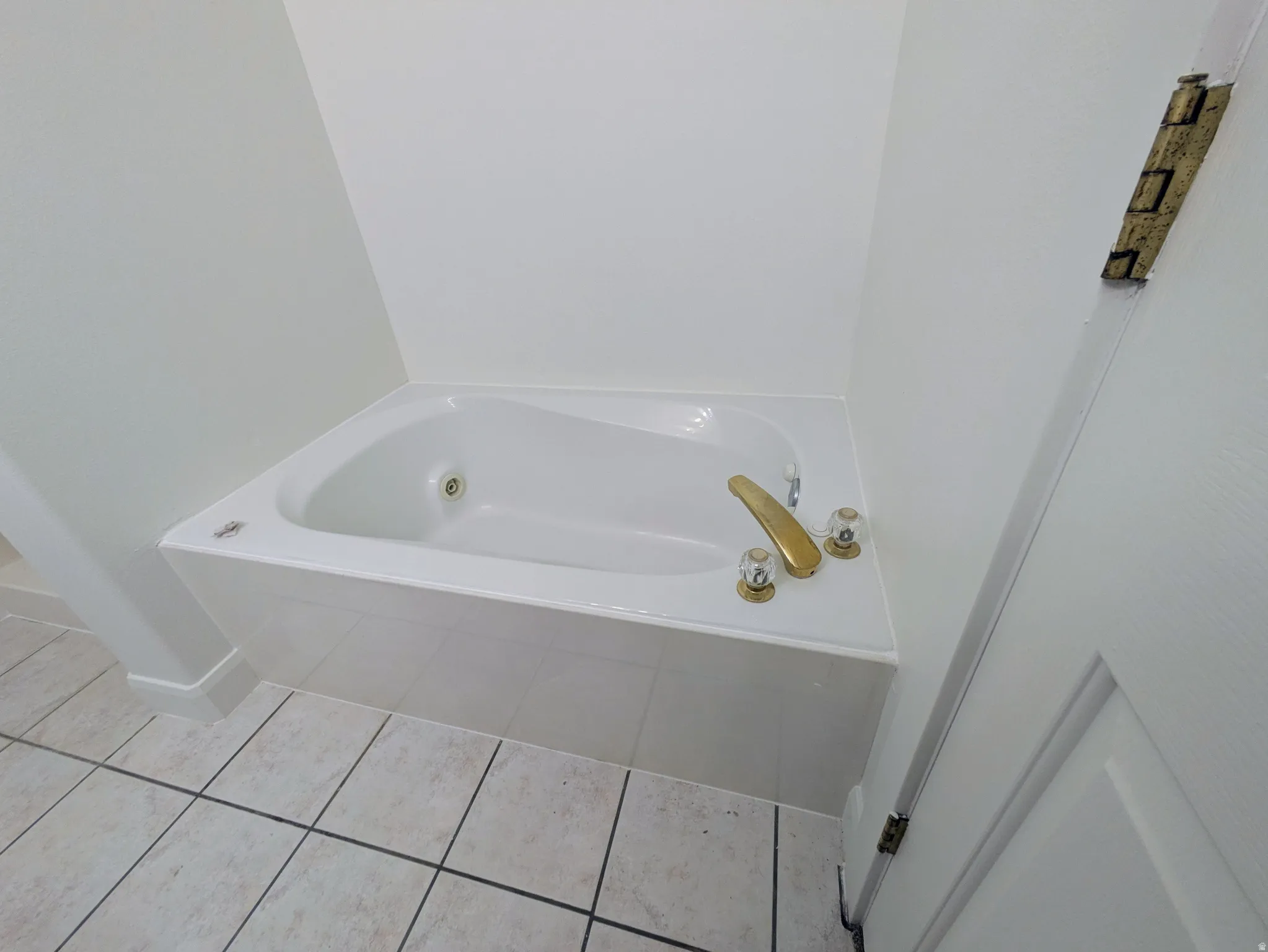Built-in soaking tub with gold-tone fixtures and clear knob handles