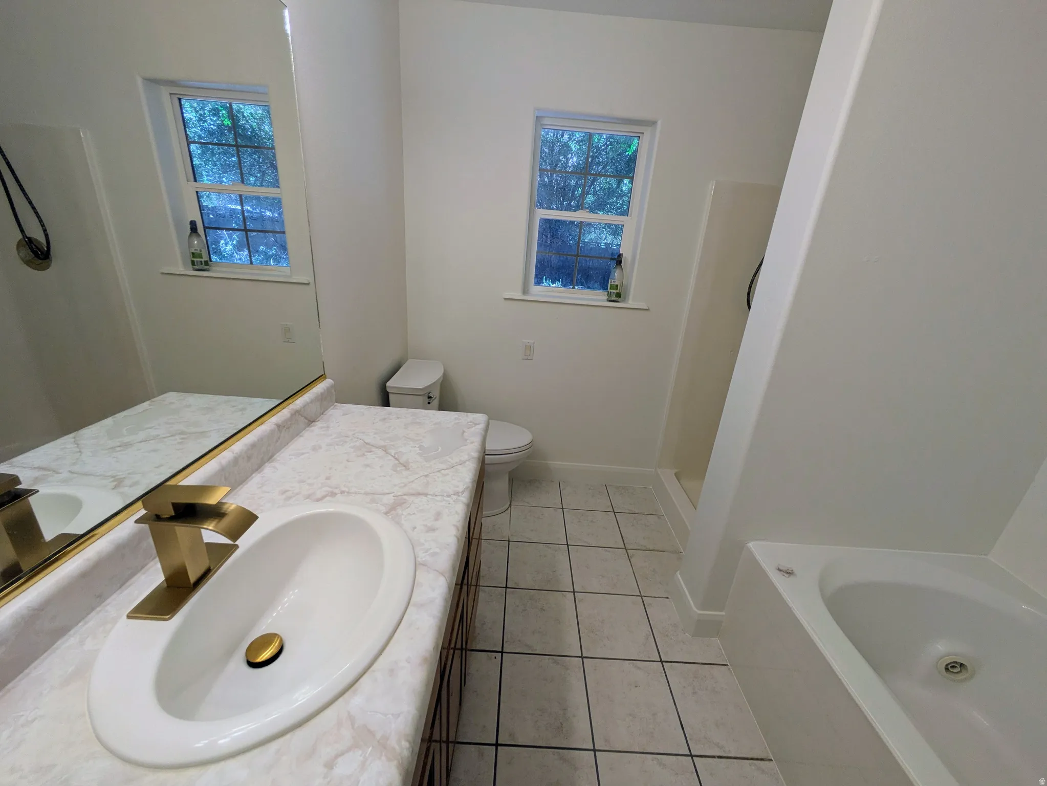 Bathroom featuring a single vanity with a gold-tone faucet, a white undermount sink, and a marble-finish countertop