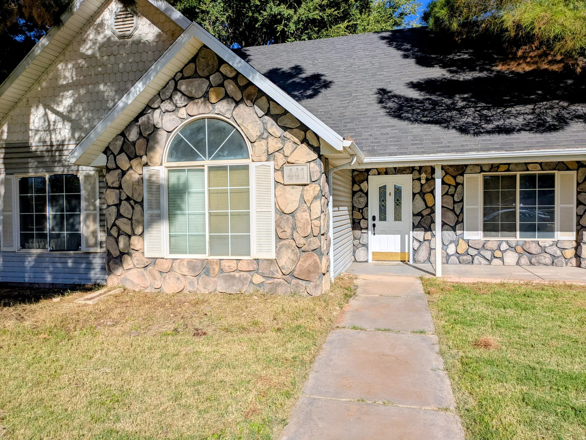 Stone facade detailing with white framed windows and decorative shutters