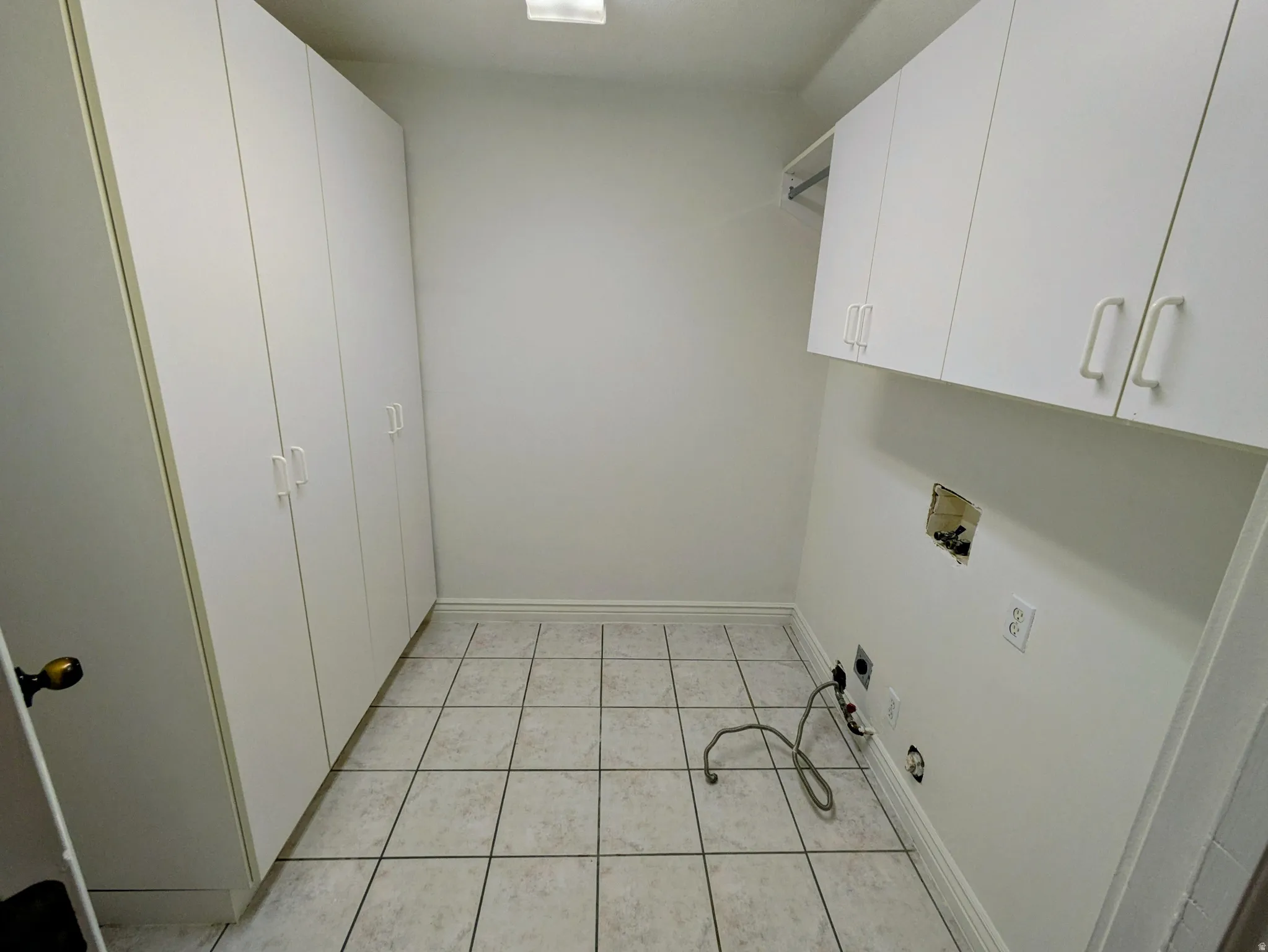 White shaker-style cabinetry, tiled flooring, and multiple hookups for appliances