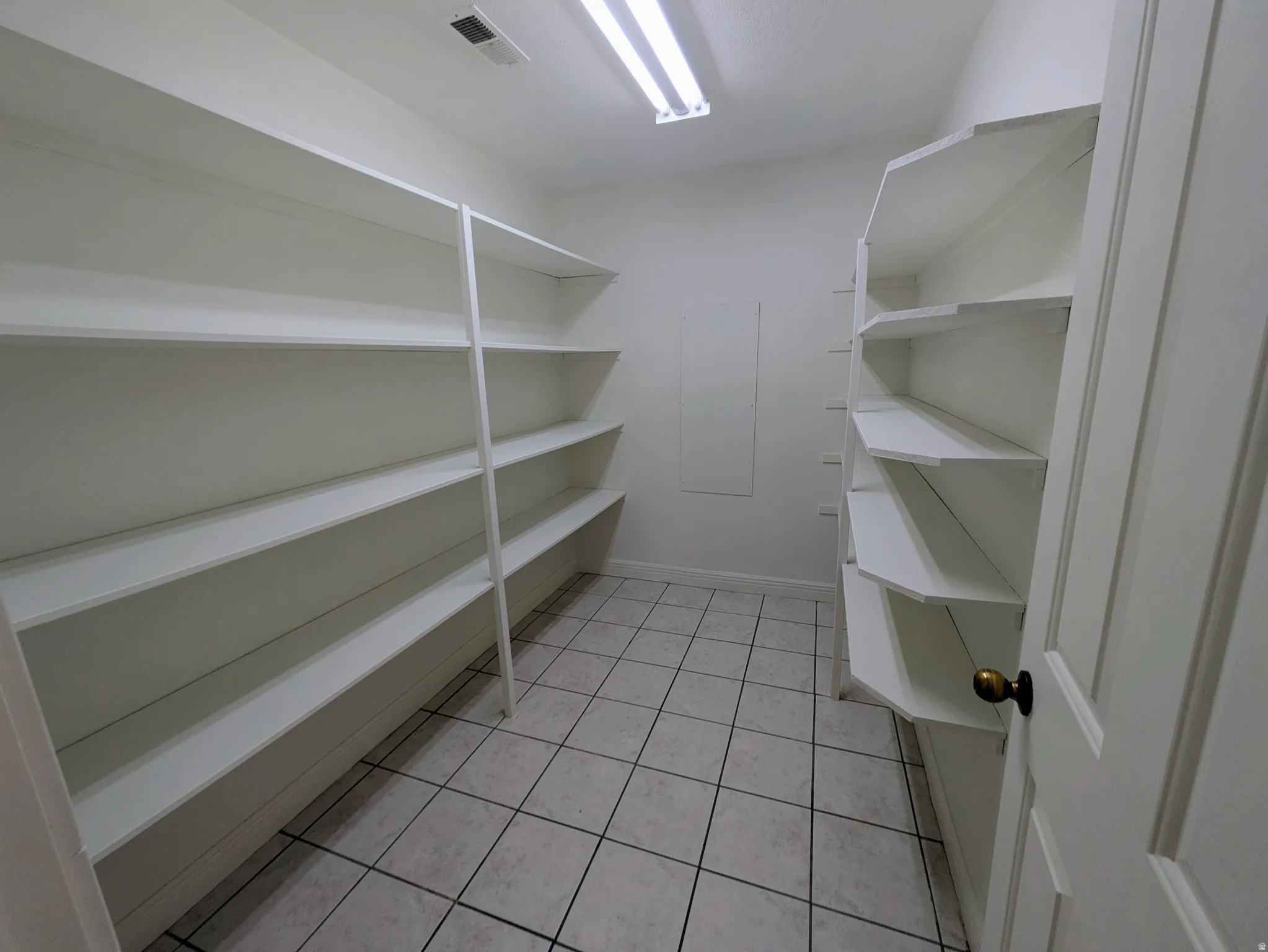 Walk-in pantry featuring built-in shelving, tile flooring, and a flush-mount overhead light fixture