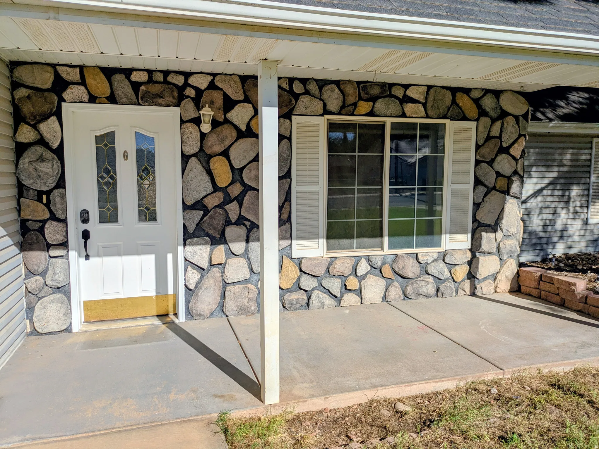 Stone facade exterior with an inviting entry door, decorative glass inserts, and an overhead light fixture