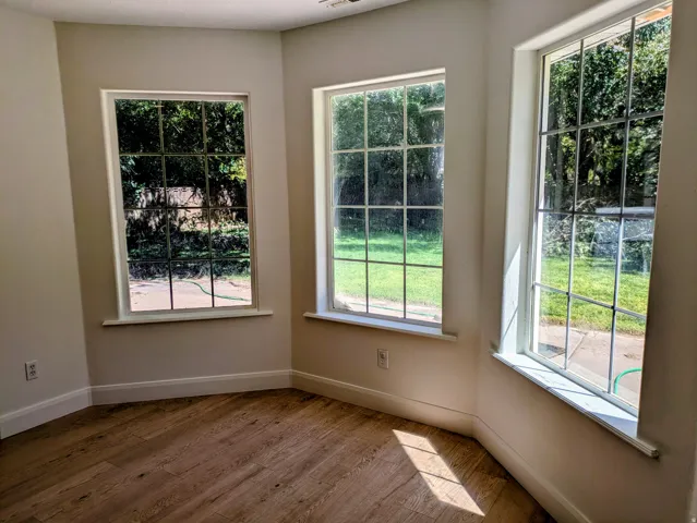 Bright interior space featuring multiple grid-pattern windows, wood-finish flooring, and crisp white trim