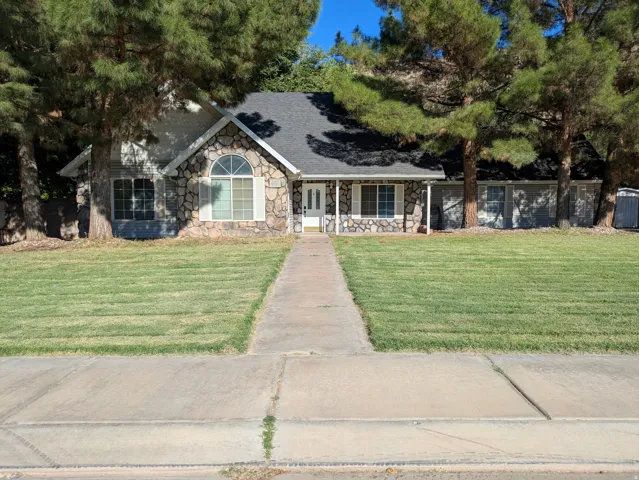 Stone facade with arched window, columned front porch, and mature trees framing the property