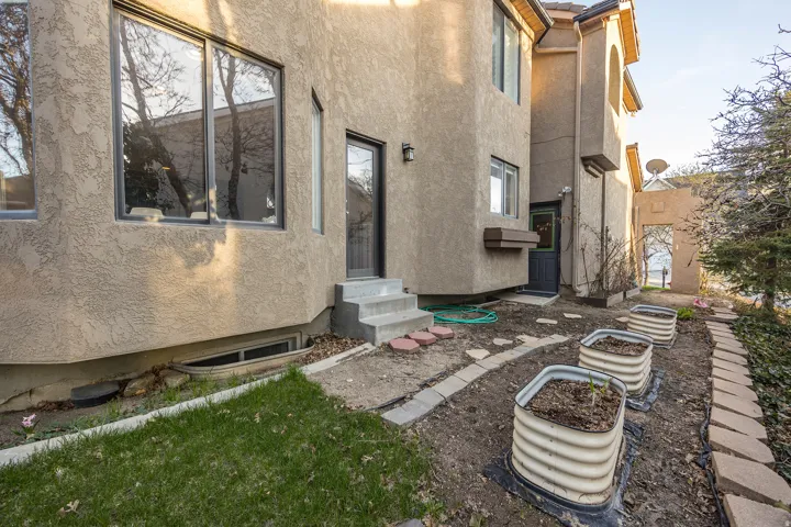 Stucco exterior with multiple windows, concrete steps, and a built-in window box