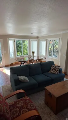 Bay window with multiple panes, crown molding, wood-finish flooring, and a glass-paneled exterior door