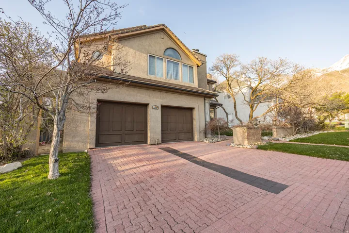 Stucco exterior with a tiled roof, arched window, and dual garage doors