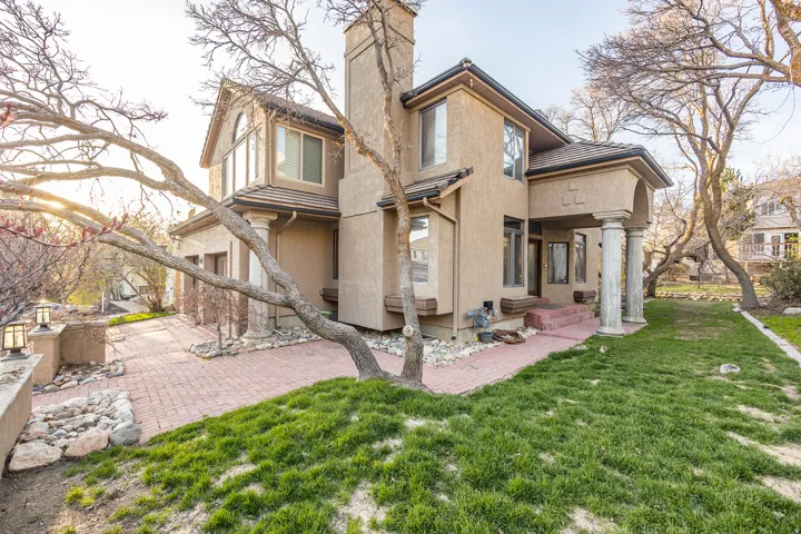 Stucco exterior with multiple bay windows, a prominent chimney, and a covered entry with columns