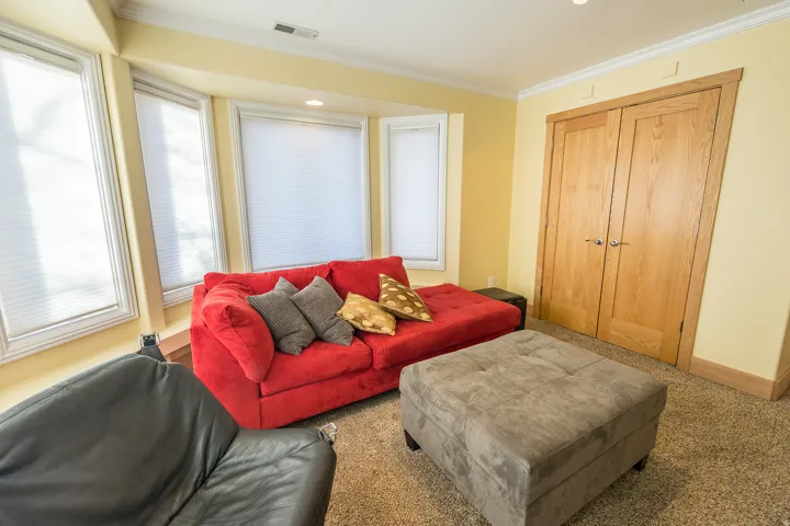 Bay window with multiple window panes, neutral carpeting, light-toned walls, wood-finish double doors, and crown molding