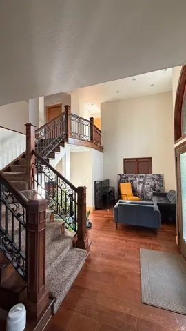 Two-story foyer featuring wood-finish flooring, a grand staircase with wrought iron balusters, and recessed lighting