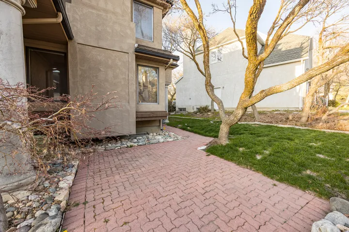 Stucco exterior, paver walkway, bay window, landscaped rock bed, and established trees