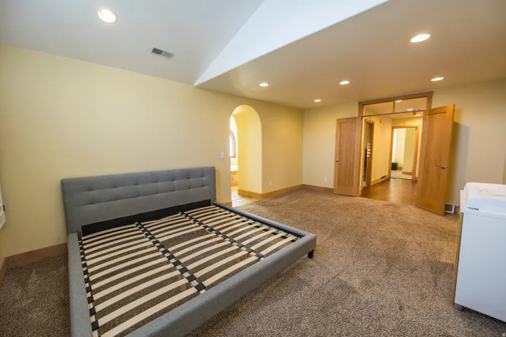 Carpeted flooring, recessed lighting, vaulted ceiling, wood-finish doors, and an arched doorway