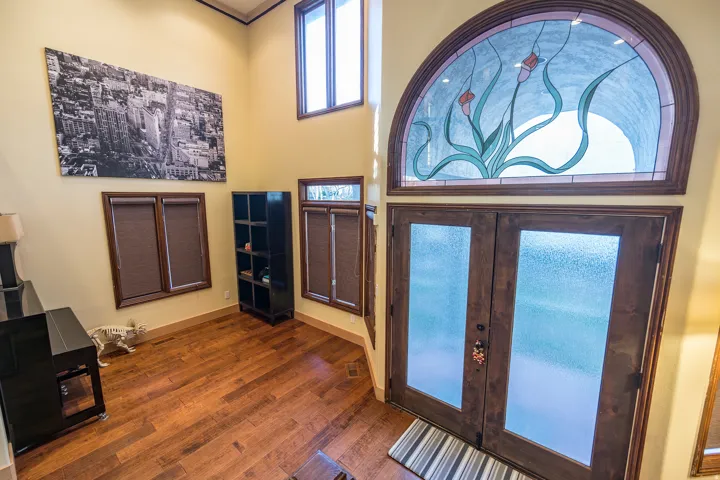 Entryway with wood-finish flooring, a double-door entry, and an arched stained-glass transom