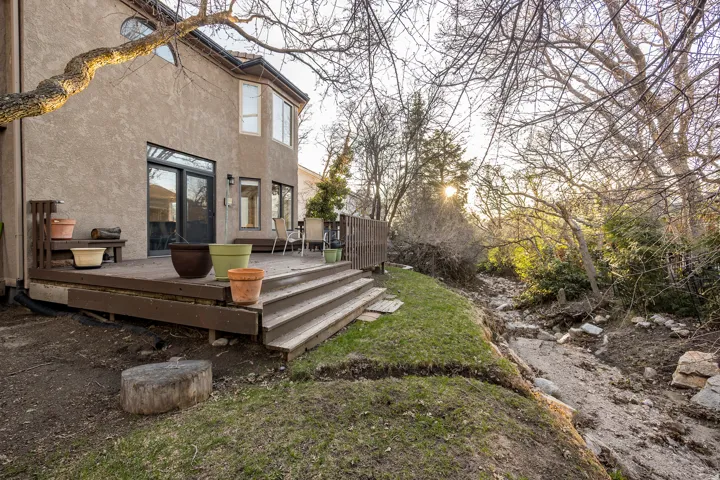 Rear exterior featuring a multi-level wooden deck with steps, a stucco exterior, and multiple windows