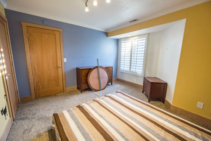 Carpeted room with wood-finish doors and trim, track lighting, and window with plantation shutters