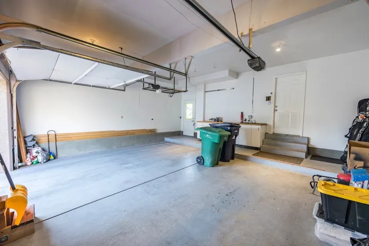 Attached garage with concrete flooring, automatic garage door opener, built-in cabinetry, and interior access doors