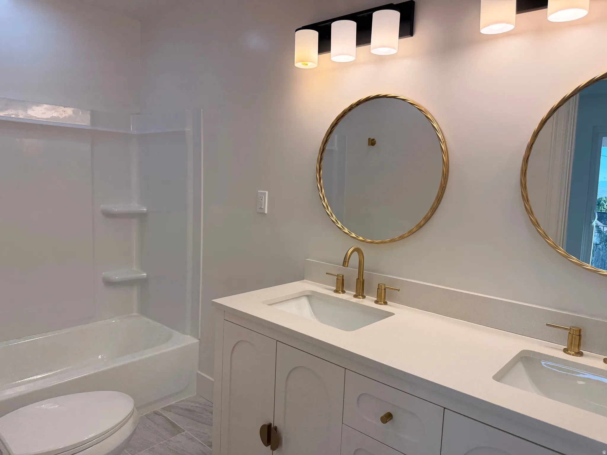 Dual vanity with integrated sinks, gold-finish hardware, and round mirrors