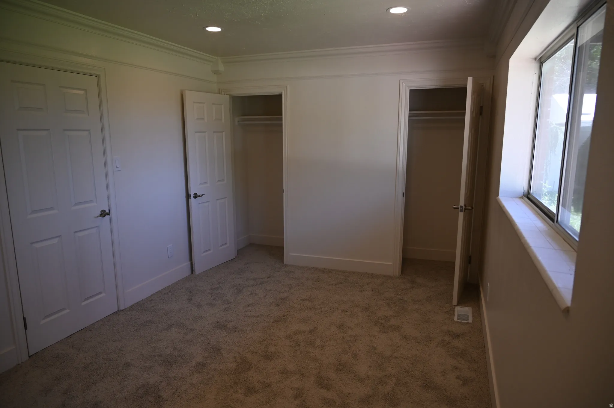 Plush carpeting, recessed lighting, crown molding, double closets with panel doors, and a window with a stone sill