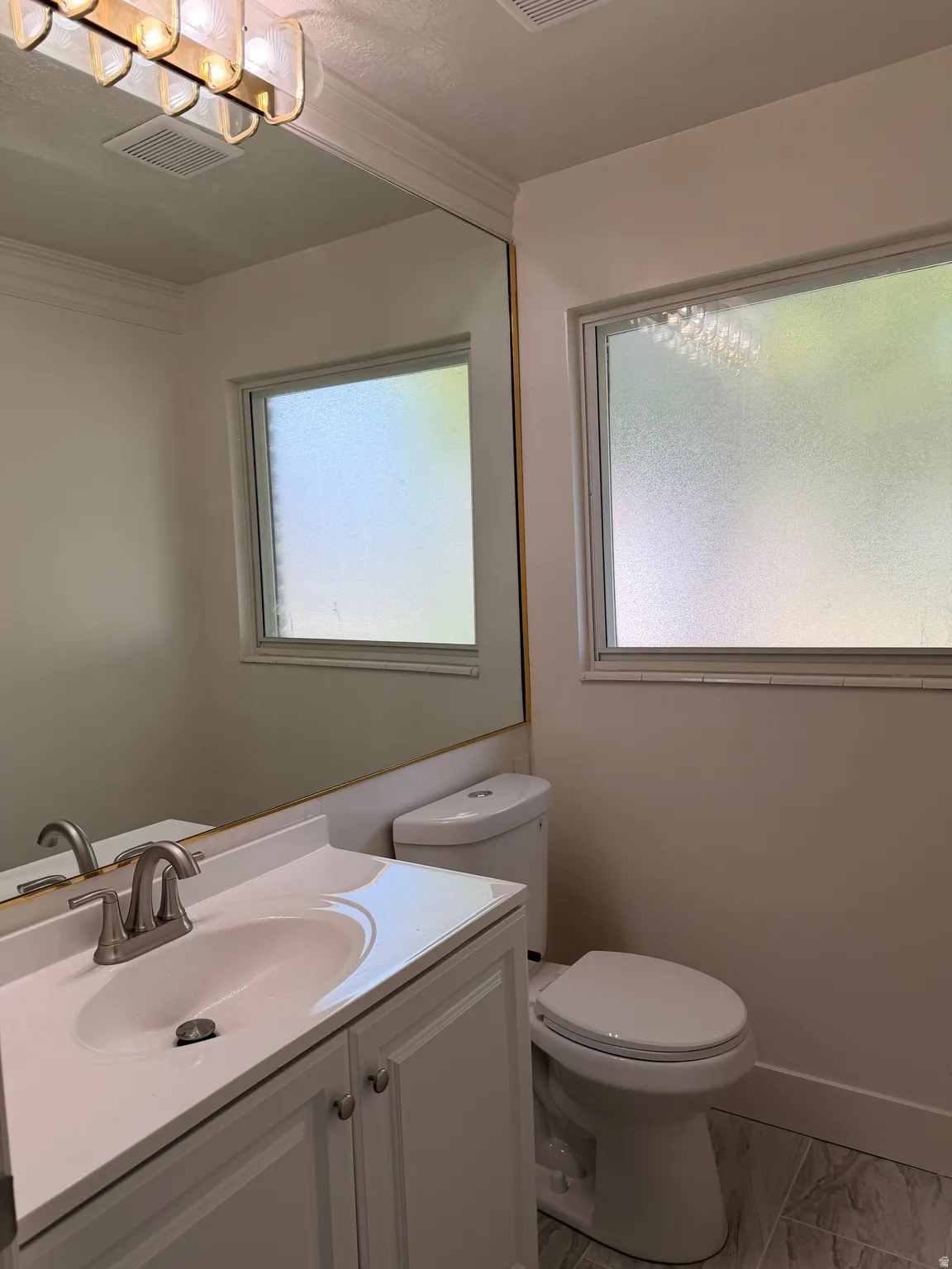White vanity with a single basin sink and brushed nickel faucet