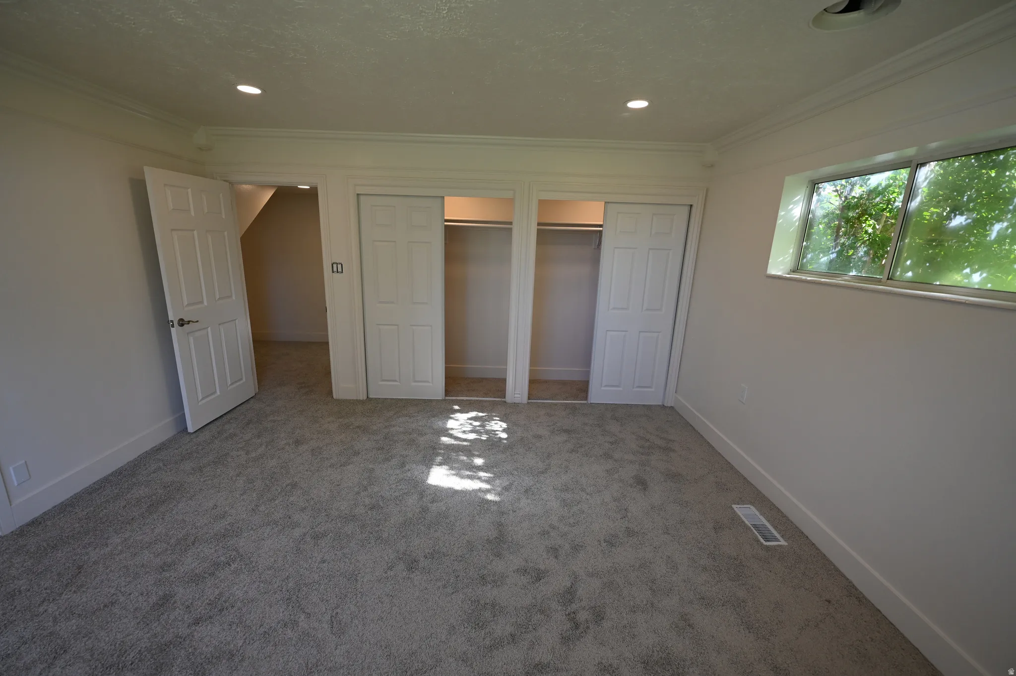 Plush carpet flooring, recessed lighting, crown molding, and a built-in closet with bi-fold doors
