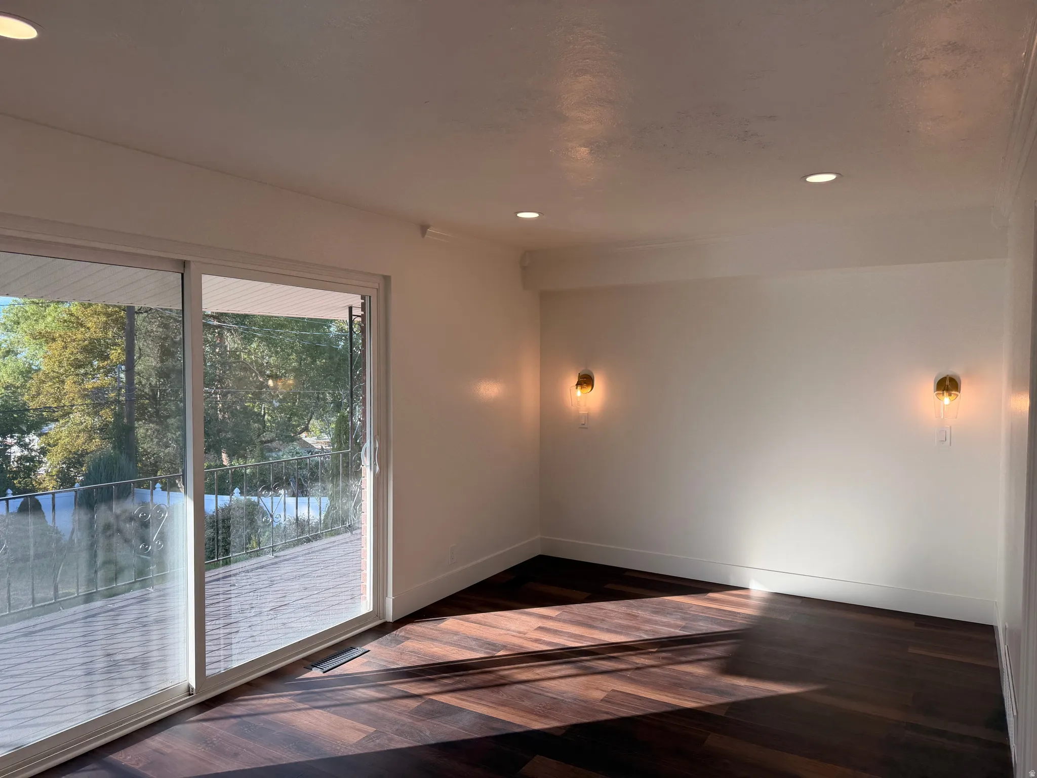 Wood-finish flooring, recessed lighting, sliding glass door, and wall-mounted sconces