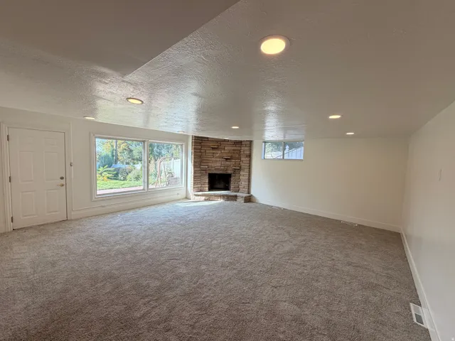 Spacious room with recessed lighting, stone fireplace, large picture windows, and light-toned carpeting