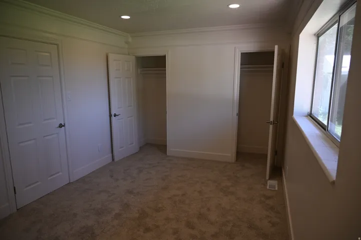Plush carpeting, recessed lighting, crown molding, double closets with panel doors, and a window with a stone sill