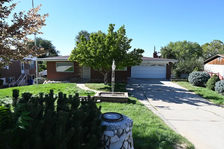 Brick exterior, attached garage, concrete driveway, front lawn, mature trees