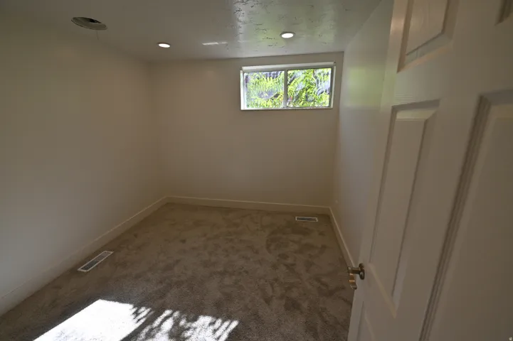 Carpeted room featuring a single window, recessed lighting, and a paneled interior door