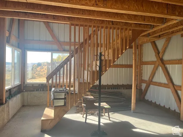 Expansive window bank, natural wood staircase, exposed wood beam construction, and concrete flooring