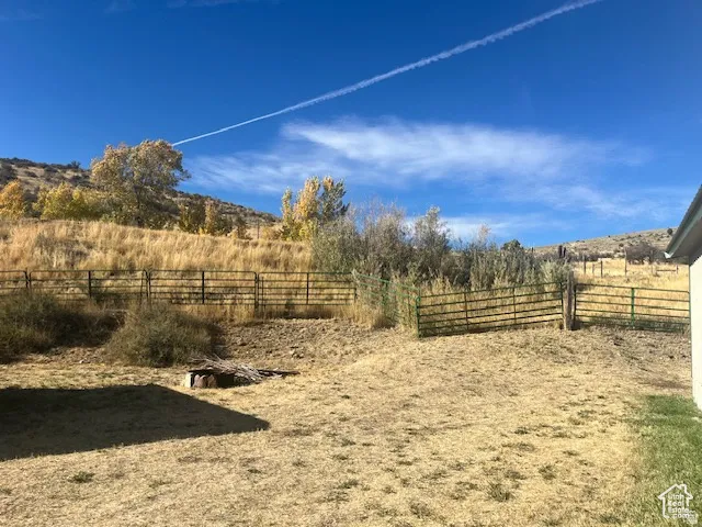 Expansive exterior space with a metal fence and natural terrain