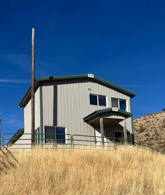 Metal siding exterior with green trim, covered entry, and multiple windows