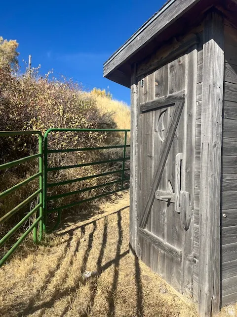 Wood-sided outdoor structure with a sloped roofline and a latching door