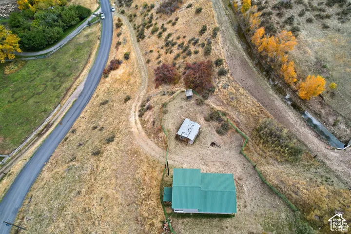 Rural property featuring a green-roofed structure, secondary outbuilding, and nearby paved road