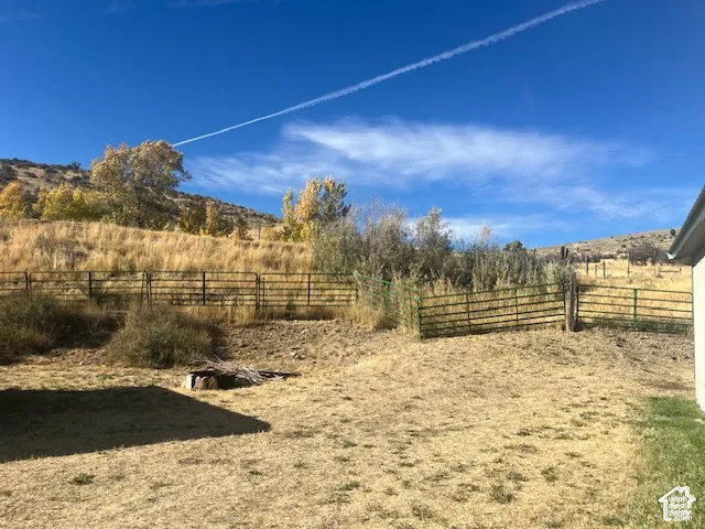 Expansive exterior space with a metal fence and natural terrain