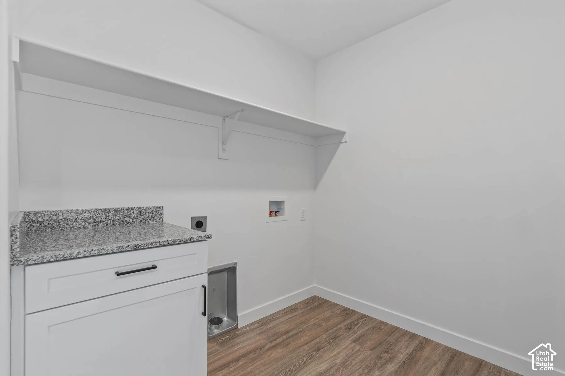 White cabinetry with black hardware, stone-finish countertop, wood-finish flooring, and wall-mounted shelving