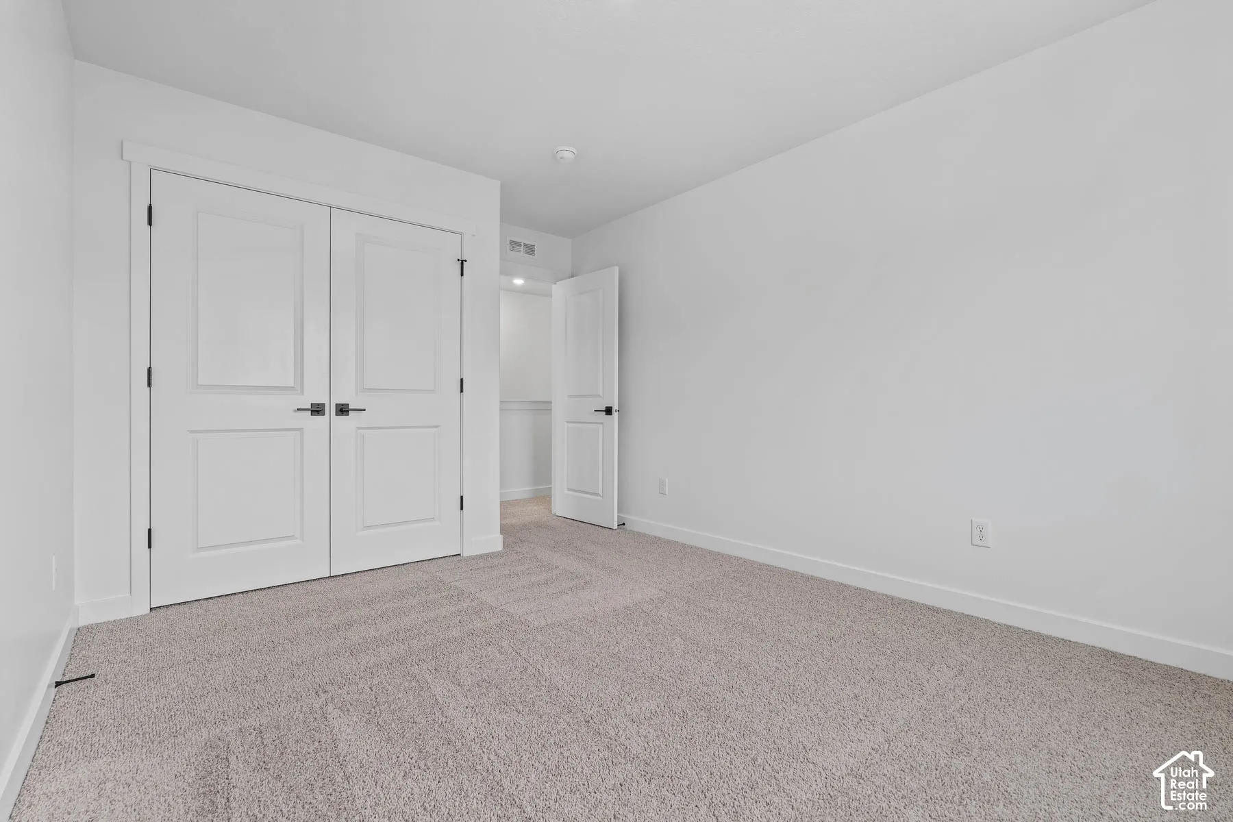 Neutral-toned carpeting, white walls, and a white paneled bi-fold door