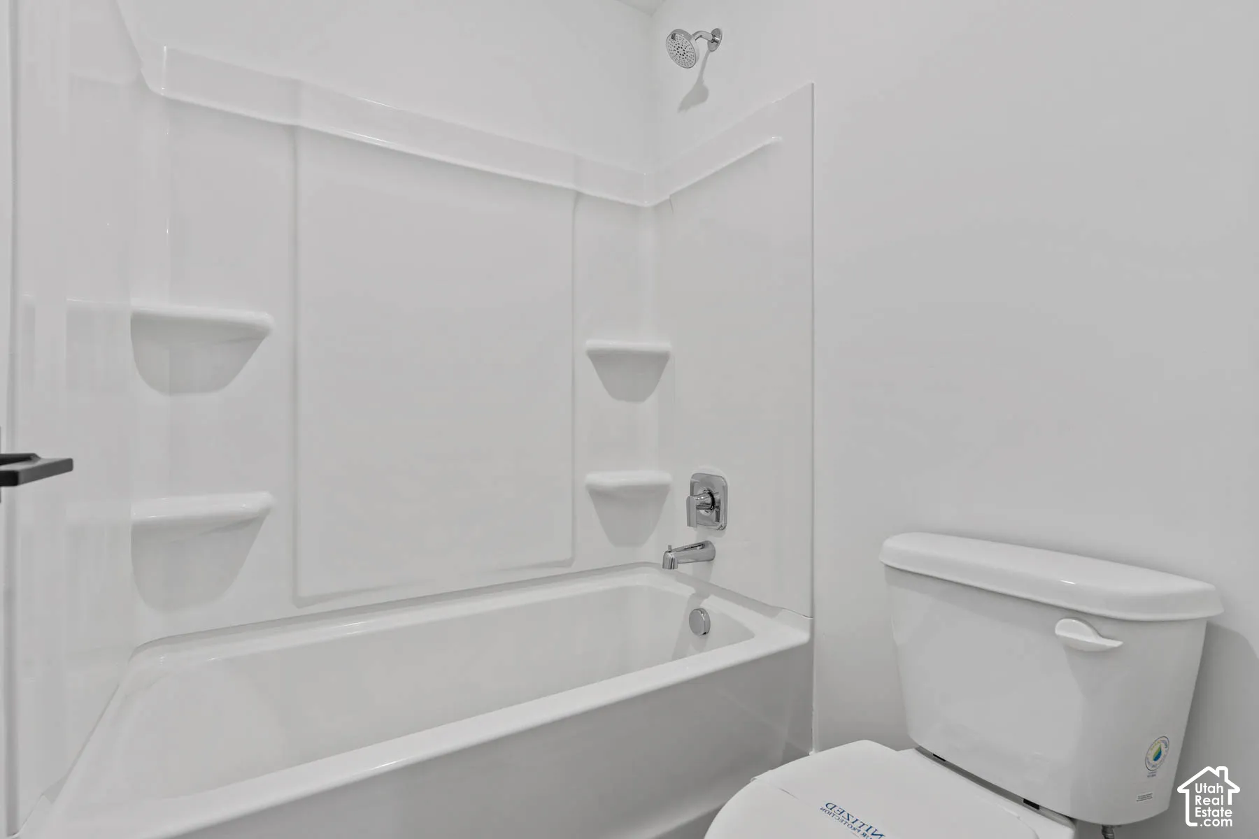 White bathtub with an integrated shower surround and chrome fixtures